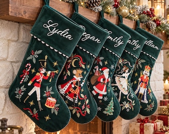 Peut inclure: Cinq chaussettes de Noël en velours vert foncé suspendues en rangée. Chaque chaussette présente un nom brodé en blanc sur le haut et une illustration de fête unique, incluant un soldat de plomb, un roi souris, le Père Noël, une danseuse et un casse-noisette.