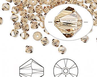 May include: A close-up of gold-toned crystal beads. The beads are faceted and have a square shape. The beads are scattered on a white background. A single bead is shown in a magnified view. A diagram of the bead's facets is also shown.