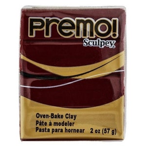 Può includere: Una confezione da 57 grammi di argilla per forno Premo! Sculpey di colore bordeaux. La confezione ha dettagli dorati e il testo "Oven-Bake Clay", "Pâte à modeler" e "Pasta para hornear" su di essa.