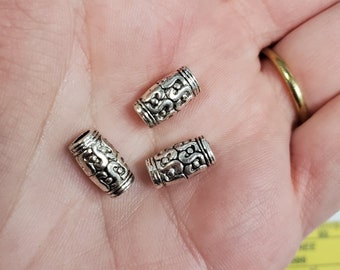 May include: Three silver metal hair beads with a decorative swirl pattern.