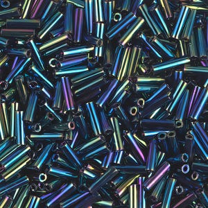 Op de afbeelding: Een close-up van een stapel iriserende buiskralen. De kralen zijn een mix van donkerblauw, blauwgroen en paars, met een metallic glans. De cilindrische kralen zijn verspreid, tonen hun open uiteinden en reflecteren licht.