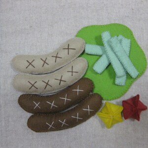 May include: Felt toy food set with four brown sausages, green felt campfire, and two felt stars, one red and one yellow.