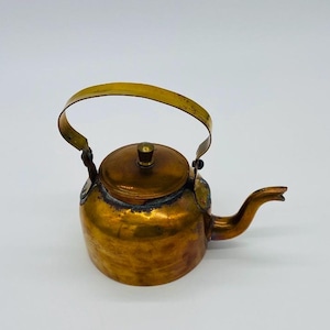 May include: A small, antique brass teapot with a tarnished finish and a brass handle.