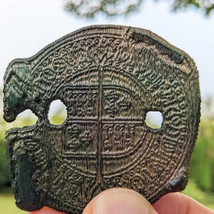 A close up detail of the 3D printed "Spanish doubloon" showing the 3 holes against a natural background