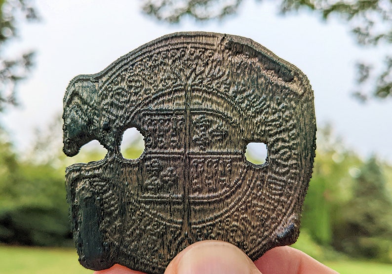 A close up detail of the 3D printed "Spanish doubloon" showing the 3 holes against a natural background
