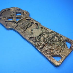An angled view of the front of the Goonies Copper Bones Key showing detail of the round symbol at the bottom