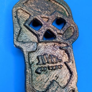 A detailed view of the top 'skull' portion of the copper bones key against a blue background
