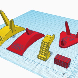 May include: Five different 3D printed display stands for action figures. The stands are made of red and yellow plastic and feature the words "Star Wars" printed on them.