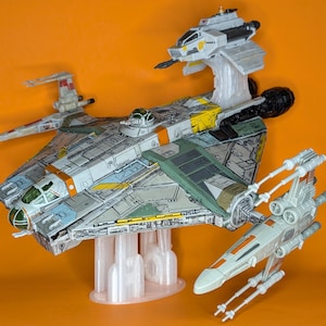 May include: A green, white and yellow spaceship with a white and orange fighter jet attached to the top. A white and orange fighter jet is attached to the bottom. All three ships are on clear plastic stands.