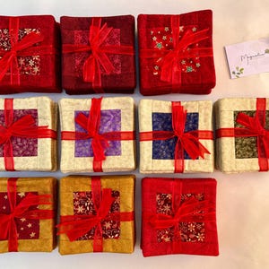 May include: Nine square fabric coasters with a gift box design. Each coaster features a different patterned fabric with red ribbon and a bow. The coasters are arranged in three rows of three.
