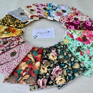 May include: A collection of fabric wallets with various floral and patterned designs. Each wallet features a decorative button closure. The color palette includes pinks, greens, yellows, and blues. The wallets are arranged in a circular pattern.