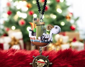 May include: A necklace with a detailed ship pendant, featuring a sheep-like figurehead and a bronze-coloured skull and crossbones pendant. The ship is multi-coloured. The necklace has a black beaded chain, set against a blurred Christmas tree background.