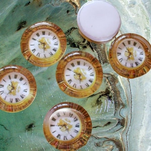 May include: Six round, glass clock face cabochons with gold trim and Roman numeral markings. The clock faces are set against a green and brown marbled background.