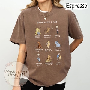 K&ouml;nnte beinhalten: Ein braunes T-Shirt mit einem Winnie Puuh-Design. Das Shirt zeigt den Text "God Says I Am" und ein Raster mit Winnie Puuh-Charakteren mit Bibelversen.