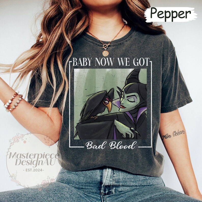 May include: Dark grey t-shirt featuring a graphic of Maleficent and a raven with the text "BABY NOW WE GOT" above and "Bad Blood" below. The shirt has a vintage, worn look.