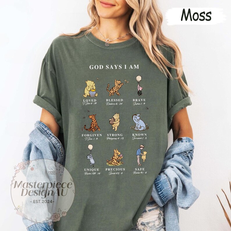 K&ouml;nnte beinhalten: Ein gr&uuml;nes T-Shirt mit dem Text "GOD SAYS I AM" und einer Reihe von Winnie Puuh-Charakteren mit Bibelversen unter jedem Charakter. Die Charaktere sind Winnie Puuh, Tigger, Ferkel, Esel und K&auml;nguruh.
