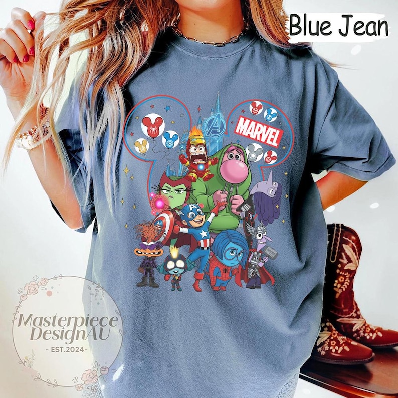 Może przedstawiać: Niebieska koszulka dżinsowa z kolorową grafiką postaci Disneya i Marvela. Projekt zawiera napis "Marvel" i słowa "Blue Jean". Koszulka ma luźny kr&oacute;j.