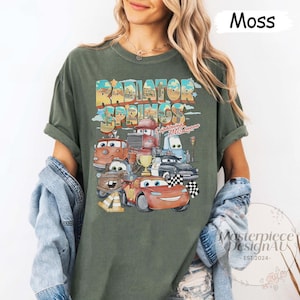 May include: A green t-shirt with a vintage-style graphic of the Cars characters from the Disney Pixar movie Cars. The graphic features the text "Radiator Springs" and "Lightning McQueen".
