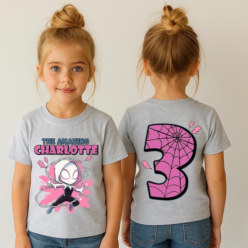 Pu&ograve; includere: Maglietta grigio chiaro con un personaggio dei cartoni animati e la scritta "THE AMAZING CHARLOTTE" in rosa e blu. Il retro della maglietta mostra un grande numero 3 rosa con un disegno a ragnatela. La maglietta &egrave; per un bambino.