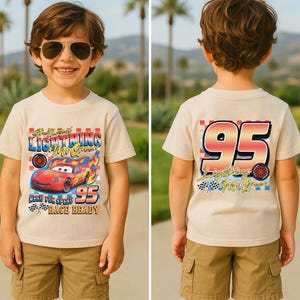 Puede incluir: Camiseta beige de manga corta con Lightning McQueen de la pel&iacute;cula Cars. El frente muestra "Lightning McQueen", "95" y "Race Ready". La parte posterior de la camiseta tambi&eacute;n muestra "95" y "Lightning McQueen".