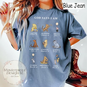 K&ouml;nnte beinhalten: Ein blaues T-Shirt mit einem Winnie-the-Pooh-Motiv. Das Shirt tr&auml;gt den Text "God Says I Am" und enth&auml;lt Bibelverse sowie Illustrationen von Winnie-the-Pooh-Charakteren.