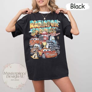 May include: Black t-shirt with a graphic print of the Cars characters from the movie Cars. The graphic features the text "Radiator Springs" and "Lightning McQueen".