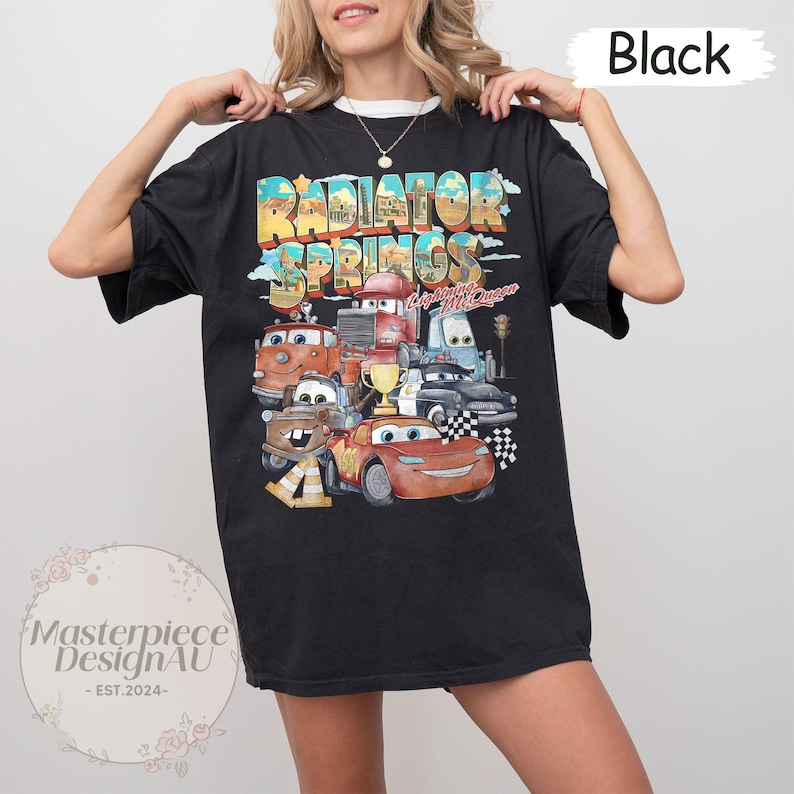 May include: Black t-shirt with a graphic print of the Cars characters from the movie Cars. The graphic features the text "Radiator Springs" and "Lightning McQueen".