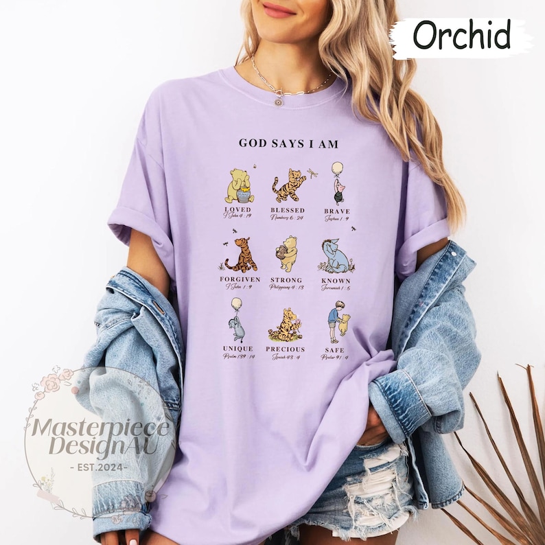 K&ouml;nnte beinhalten: Ein lila T-Shirt mit einem Winnie-the-Pooh-Motiv. Das Shirt zeigt ein Zitat "Gott sagt, ich bin" mit einer Liste positiver Affirmationen und Bibelversen.