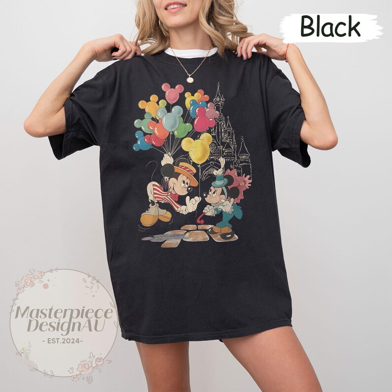 May include: Black t-shirt featuring Mickey Mouse and Minnie Mouse holding balloons in front of Cinderella's Castle.