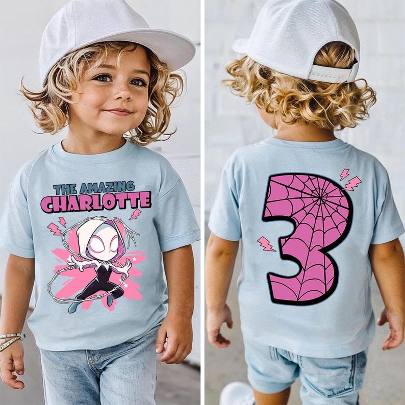 Pu&ograve; includere: T-shirt azzurra con grafica di supereroe e la scritta "THE AMAZING CHARLOTTE" sul davanti. Il retro della maglietta mostra un numero 3 rosa con un disegno a ragnatela e fulmini.