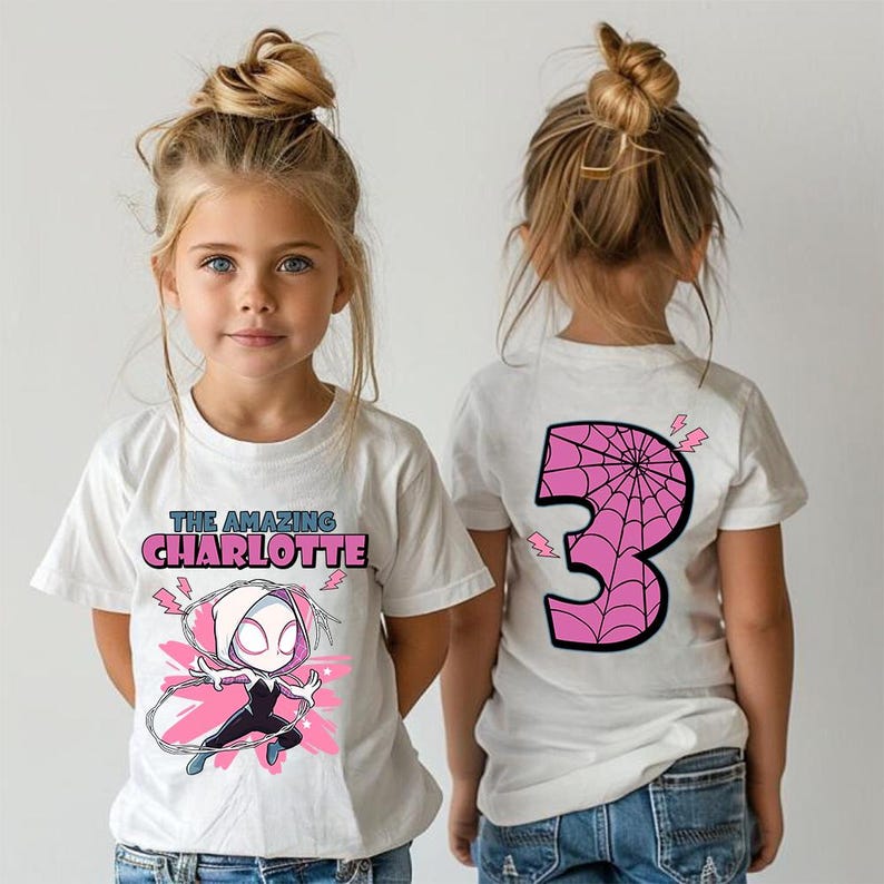 Pu&ograve; includere: Due magliette bianche con una grafica di supereroe. Una maglietta mostra la scritta "THE AMAZING CHARLOTTE" e un'illustrazione del personaggio. L'altra ha un grande numero 3 rosa con un disegno a ragnatela.