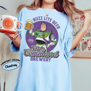 May include: A white ceramic mug with a black handle and the text "But First, Coffee" in a bold, black font. The mug is filled with a dark liquid, likely coffee, and sits on a light-colored surface.