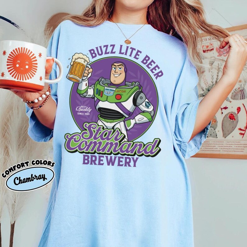 May include: A white ceramic mug with a black handle and the text "But First, Coffee" in a bold, black font. The mug is filled with a dark liquid, likely coffee, and sits on a light-colored surface.