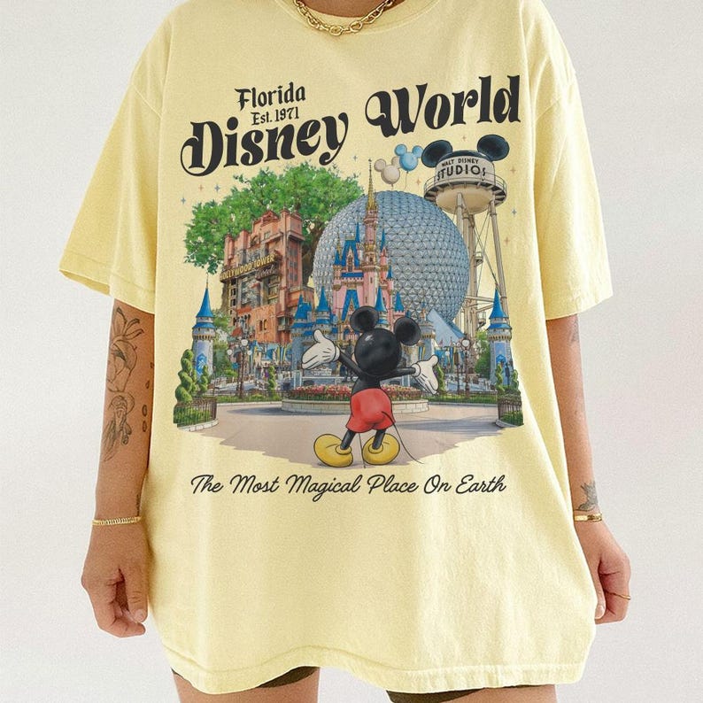 May include: A light yellow t-shirt featuring a colorful graphic of Disney World in Florida, with Mickey Mouse in the foreground. The text "Florida Disney World" and "The Most Magical Place On Earth" are also printed on the shirt.