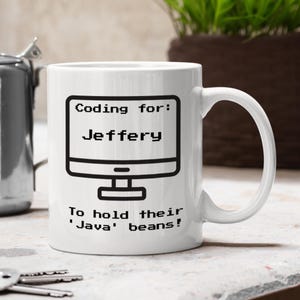 May include: White ceramic mug with a black computer screen graphic and the text "Coding for: Jeffery" above the screen. Below the screen, the text reads "To hold their 'Java' beans!"