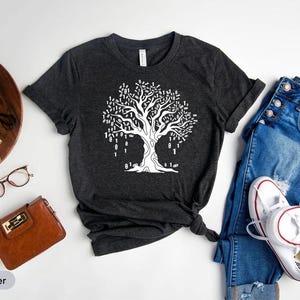 a casual outfit consisting of a black t-shirt with a tree graphic, a pair of blue jeans, white sneakers, and a brown wallet.