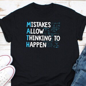 Puede incluir: Camiseta negra con el texto "MISTAKES ALLOW MATH THINKING TO HAPPEN" en blanco y azul claro. La camiseta también presenta fórmulas y diagramas matemáticos en azul claro. Zapatillas blancas visibles en la esquina inferior izquierda.