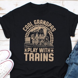 May include: Black t-shirt with a vintage illustration of a steam train and the text "Cool Grandpas Play With Trains".
