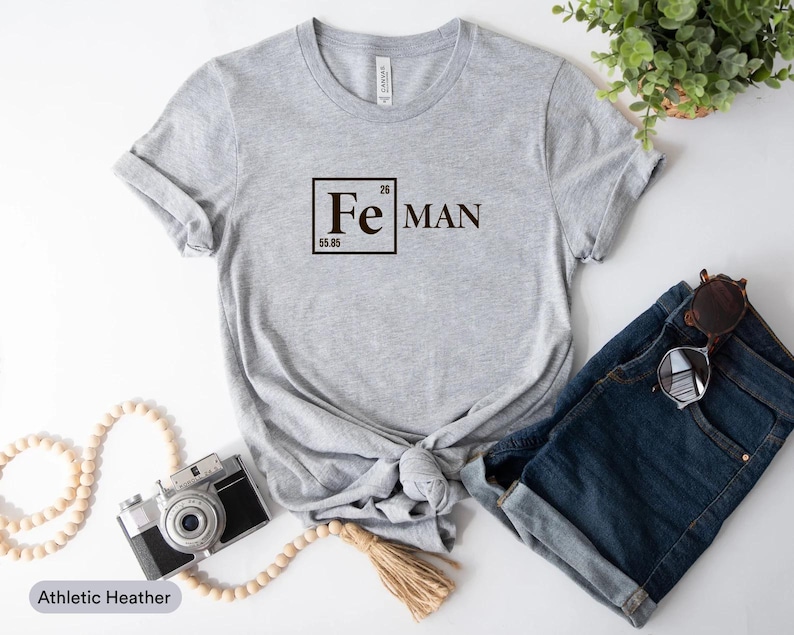a casual outfit consisting of a gray t-shirt with a chemical element design, a pair of denim shorts, a camera, and a potted plant.