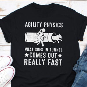 Könnte beinhalten: Schwarzes T-Shirt mit weißem Text, der "Agility Physics What Goes In Tunnel Comes Out Really Fast" lautet. Der Text wird von einer Grafik einer Person und eines Hundes begleitet, die durch einen Tunnel laufen.