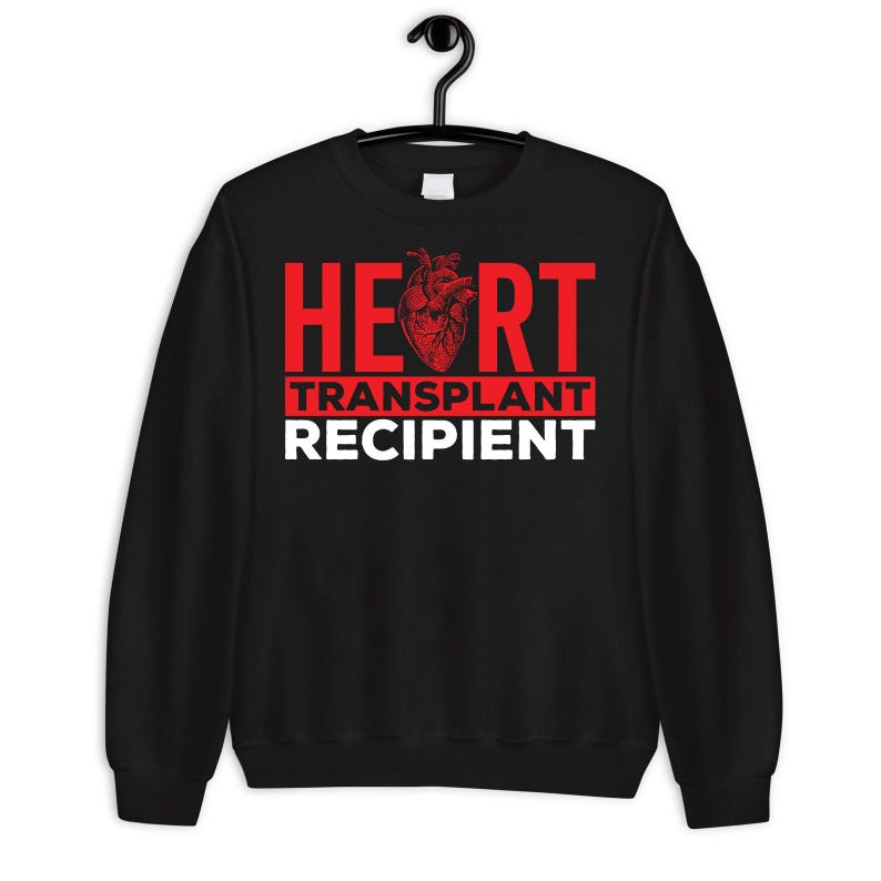 May include: Black sweatshirt with red text that reads "HEART TRANSPLANT RECIPIENT" with a red anatomical heart graphic.