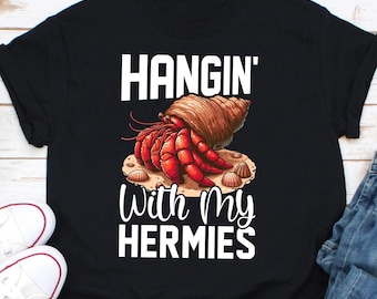 May include: Black t-shirt with a white graphic of a hermit crab in a shell and the text "Hangin' With My Hermies".