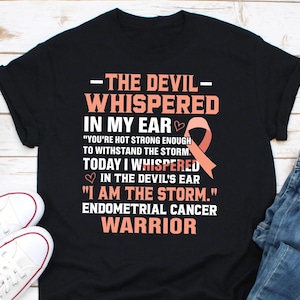 Puede incluir: Camiseta negra con una cinta rosa y el texto "The Devil Whispered in My Ear "You're Hot Strong Enough to Withstand the Storm. Today I Whispered in the Devil's Ear "I Am the Storm." Endometrial Cancer Warrior"