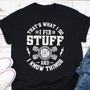 May include: Black t-shirt with white text that reads "That's what I do I fix stuff - and - I know things". The text is surrounded by a graphic of a wrench and gears.