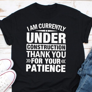 Puede incluir: Camiseta negra con texto blanco que dice "Estoy actualmente en construcción gracias por su paciencia".