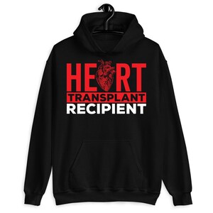 May include: Black hooded sweatshirt with the text "HEART TRANSPLANT RECIPIENT" in red letters and a red anatomical heart graphic.
