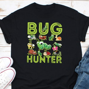 May include: Black t-shirt with the words "BUG HUNTER" in green, featuring cartoon illustrations of various insects. The shirt includes a bee, caterpillar, ladybug, spider, and other bugs.