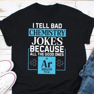 May include: Black t-shirt with a blue and white graphic that says "I tell bad chemistry jokes because all the good ones Ar gone". The graphic features the chemical symbol for Argon, Ar, with the atomic number 18 and atomic weight 39.948.