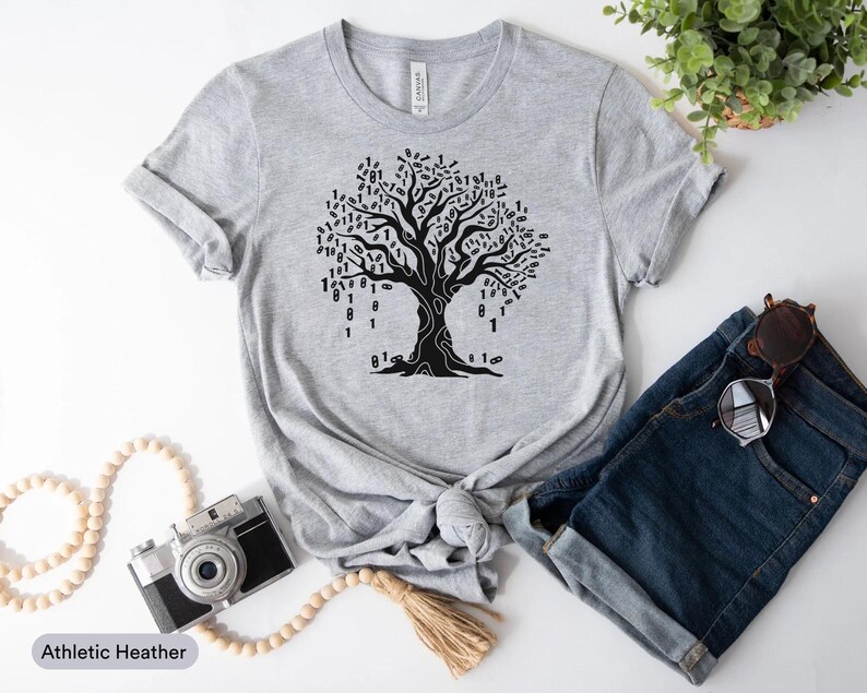 a casual outfit consisting of a gray t-shirt with a tree graphic, a pair of blue jeans, a pair of sunglasses, a camera, and some beads.