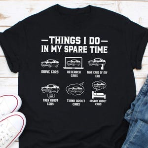 May include: A black t-shirt with white text that reads "Things I do in my spare time". The text is followed by six icons depicting different activities related to cars, including driving, researching, taking care of, talking about, thinking about, and dreaming about cars.